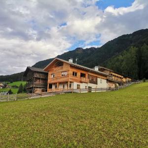 a large barn with a field in front of it at Ritschhof in Castelrotto