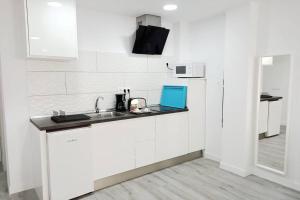 eine weiße Küche mit einer Spüle und einer Mikrowelle in der Unterkunft Precioso apartamento a 150 metros de la Playa in Las Palmas de Gran Canaria
