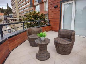 Un balcón con tres sillas y una planta en maceta. en Departamento Bariloche centro, en San Carlos de Bariloche