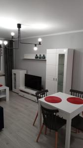 - un salon avec une table, des chaises et une télévision dans l'établissement Apartament Jakubek, à Polkowice