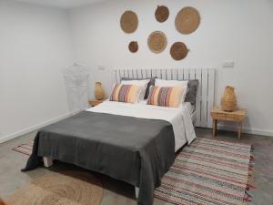 1 dormitorio con 1 cama y 2 cestas en la pared en Casa da Duna, Carvalhal, Comporta, en Carvalhal