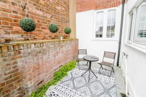 un patio con mesa y sillas junto a una pared de ladrillo en New city house, great location - with parking, en Norwich