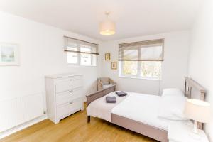 a white bedroom with a bed and two windows at Cosy City Centre Apartment With Parking in Norwich