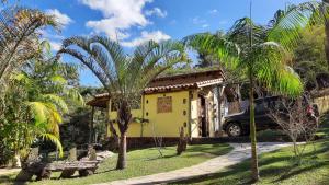 a yellow house with palm trees in front of it at Pousada Serra da Matinha - vegetariana in São João Batista do Glória