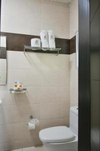 a bathroom with a toilet and towels on shelves at Hotel Portonovo Plaza Centro in Guadalajara
