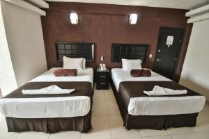 a hotel room with two beds with white sheets at Hotel Portonovo Plaza Centro in Guadalajara
