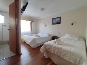 Habitación de hotel con 2 camas y espejo en HOTEL GLACIARES, en Puerto Natales