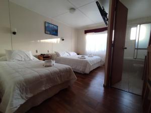 a hotel room with two beds and a bathroom at HOTEL GLACIARES in Puerto Natales