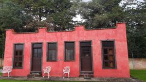 ein rotes Haus mit Stühlen davor in der Unterkunft Rio Estigia INN in Tlalpujahua