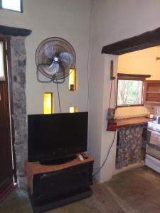 sala de estar con TV y chimenea en Casita Los Retoños en San Marcos Sierras en San Marcos Sierras