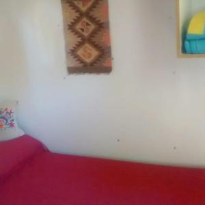 Un dormitorio con una cama roja y una pintura en la pared en Casilla Rodante Rural en San Marcos en San Marcos Sierras