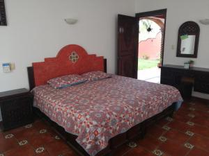 een slaapkamer met een bed met een rode sprei en een spiegel bij Hotel Villa Palmeras in Tecolutla