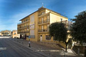 un edificio amarillo al lado de una calle en Hotel Astoria, en Fermo