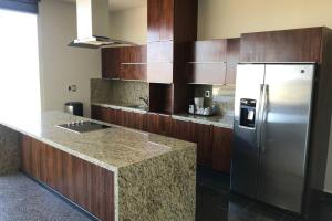 a kitchen with a stainless steel refrigerator and wooden cabinets at Penthouse en Irapuato in Irapuato