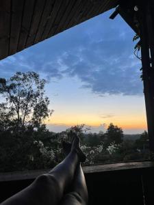 Ein Mann, der auf einem Fensterbrett mit Blick auf den Sonnenuntergang liegt. in der Unterkunft Refúgio conexão natureza! Chalet amplo e confortável ;) in Eldorado do Sul 