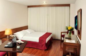 a hotel room with a bed and a desk with a laptop at Hotel Boyaca Plaza in Tunja