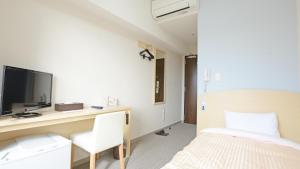 a bedroom with a bed and a desk with a television at UNIZO INN Express Utsunomiya in Utsunomiya