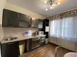 a kitchen with black cabinets and a sink and a window at Dekabrist apartment at Ugdanskaya 8 in Chita