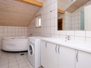 a bathroom with a washing machine and a bath tub at Holiday home Dannemare VII in Dannemare