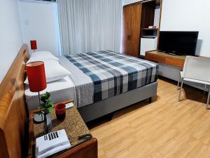 a hotel room with a bed and a television at Hotel Germânia in Joinville