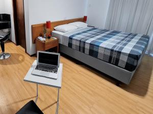 a bedroom with a bed and a laptop on a table at Hotel Germânia in Joinville +127 photos