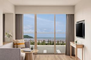 a living room with a couch and a large window at Vivanta Goa, Miramar in Panaji
