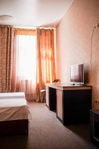 コムソモリスク・ナ・アムーレにあるBusiness Сentre Hotelのベッド、デスク、テレビが備わるホテルルームです。