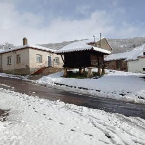 una calle cubierta de nieve con casas y un edificio en Los Tres Hórreos, en Felechas