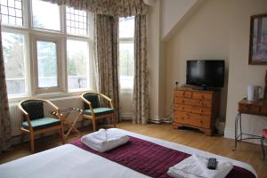 a bedroom with a bed and a tv and windows at Hylands Hotel in Coventry