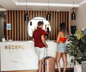 a man and woman standing at a counter with a suitcase at Hotel Lusso Mare by Aycon in Budva