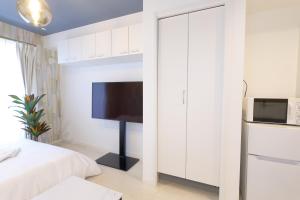 a white bedroom with a bed and a tv at AQA ART 江の島 in Fujisawa