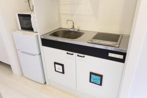 a kitchen with white cabinets and a sink and a refrigerator at AQA ART 江の島 in Fujisawa