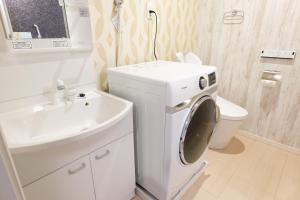 a white bathroom with a washing machine and a sink at AQA ART 江の島 in Fujisawa
