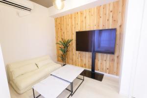 een woonkamer met een bank en een tv aan de muur bij AQA ART 江の島 in Fujisawa