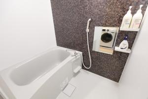 a bathroom with a bath tub with a shower at AQA ART 江の島 in Fujisawa