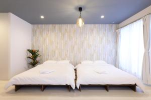 2 bedden in een slaapkamer met witte muren bij AQA ART 江の島 in Fujisawa