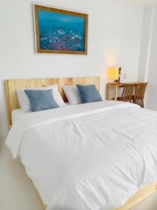 een groot bed met witte lakens en blauwe kussens bij Bannsukta in Na Jomtien