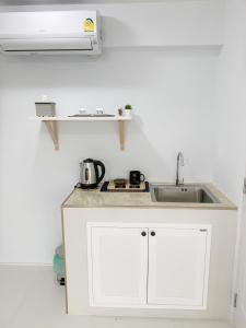 a white kitchen with a sink and a stove at Bannsukta in Na Jomtien