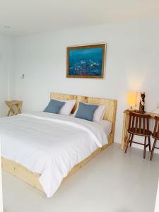 een slaapkamer met een groot bed met witte lakens en blauwe kussens bij Bannsukta in Na Jomtien