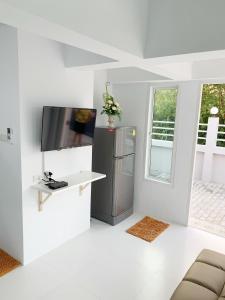 een woonkamer met een koelkast en een televisie bij Bannsukta in Na Jomtien