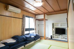 a living room with a couch and a tv at Guest House Danran in Beppu