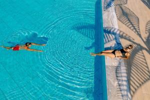 two people are swimming in a swimming pool at Ivi Mare - Designed for Adults by Louis Hotels in Paphos
