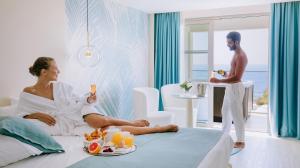a man standing in a room with a woman in a bed at Ivi Mare - Designed for Adults by Louis Hotels in Paphos