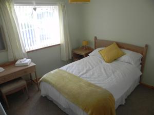a bedroom with a bed and a desk and a window at Tigh Murdag, 37D Newmarket HS2 0DT in Stornoway
