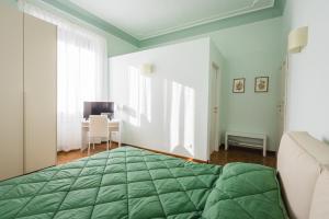 a bedroom with a green bed and a desk at Hortensia Garden in Macerata