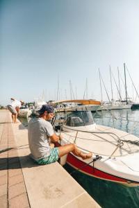 un hombre sentado en un pequeño barco en el agua en EM Kastelo Zadar, en Zadar