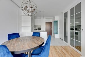 a dining room with a wooden table and blue chairs at Downtown Apartments Seaside Primore in Gdańsk