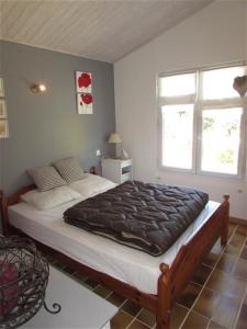 a bedroom with a large bed and two windows at Maison Vert d'Eau in Grand-Village-Plage