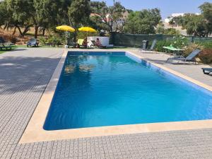 a large blue swimming pool with two umbrellas at Casa De Campo Cantinho Da Serra in Cortelha