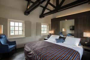 a bedroom with a large bed and a blue chair at Romantik Hotel Kasteel Daelenbroeck in Herkenbosch